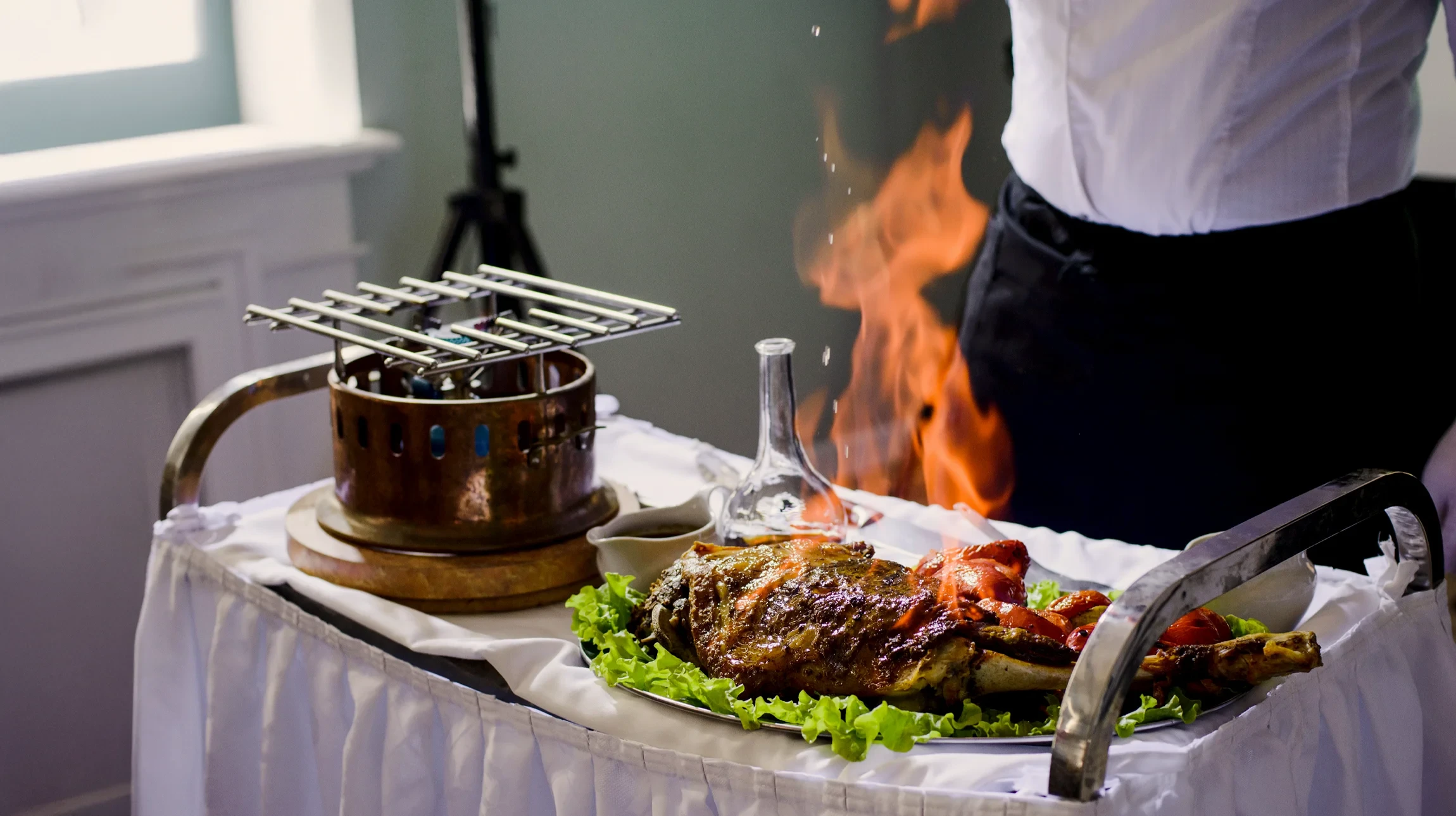 Scène de préparation culinaire en intérieur avec main tenant une part de flammekueche alsacienne découpée sur ardoise noire