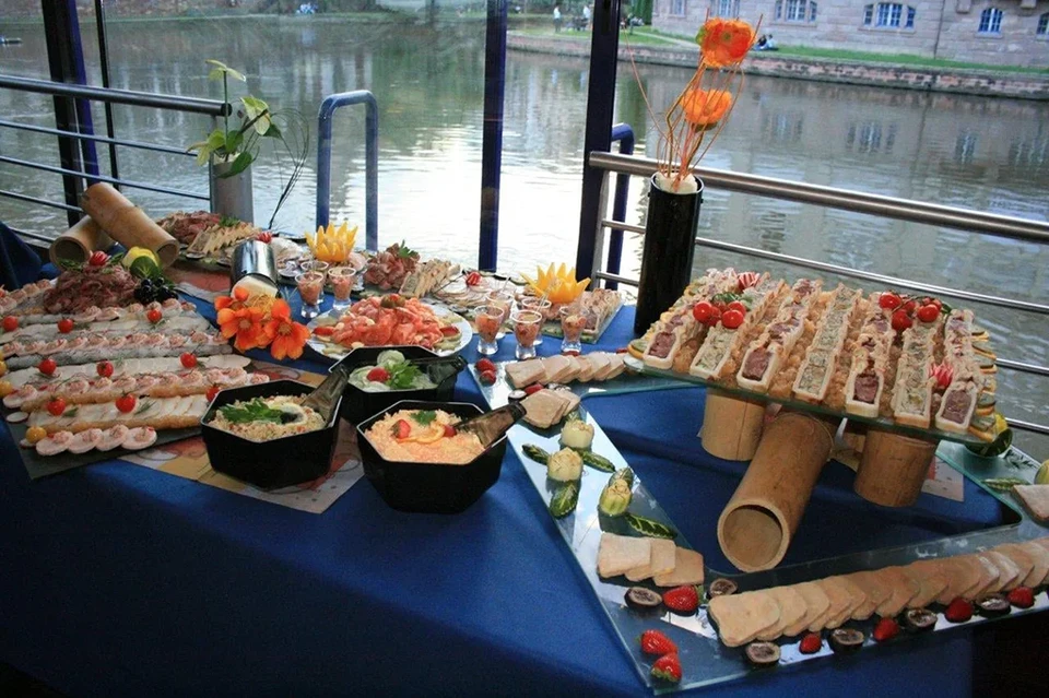 Un chef finalise le dressage d'un plat de saumon grillé dans une cuisine professionnelle, ajoutant délicatement les dernières touches de présentation avec ses mains expertes